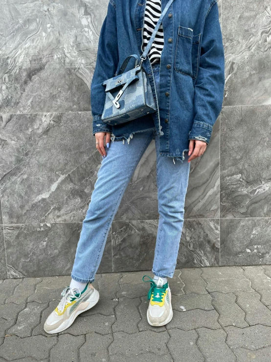 a woman stands in front of a wall wearing a striped shirt and denim jacket