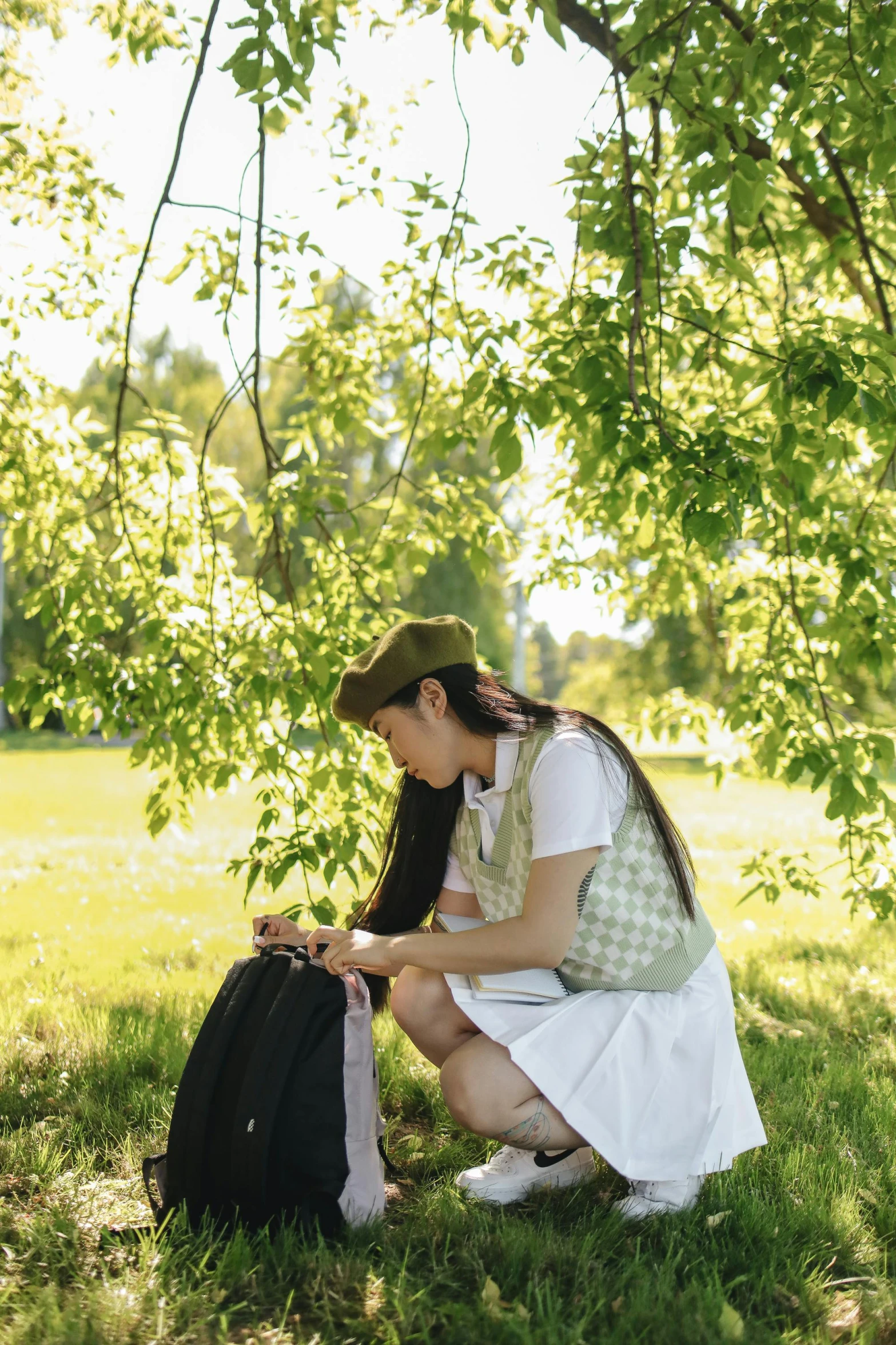 a woman kneeling in the grass with a suitcase, unsplash, visual art, dressed as schoolgirl, sitting under a tree, with a backpack, an asian woman