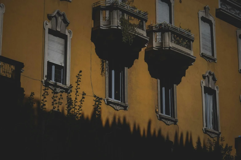 a couple of windows sitting on the side of a building, a photo, by Alessandro Allori, pexels contest winner, black and yellow color scheme, hanging gardens, low light, parapets