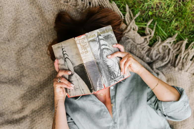 a woman covering her face with a book, a portrait, pexels contest winner, lying on the grass, photography of charline von heyl, cottage hippie naturalist, top-down view