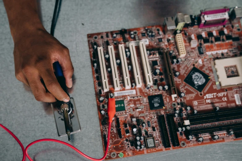 a person working on a computer mother board, an album cover, trending on pexels, brown, with electric arc device, promo image, educational