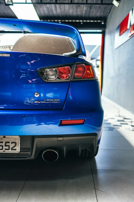 the rear end of a blue car parked in a garage