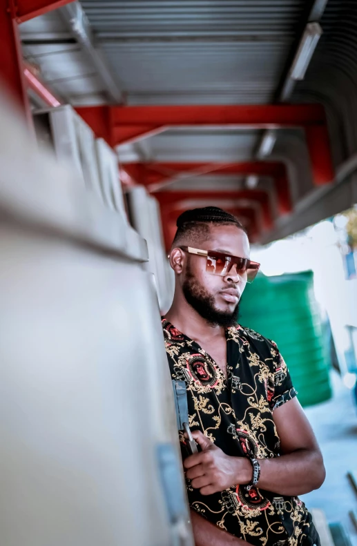 man with sunglasses leans against a wall