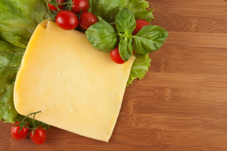 a piece of cheese sitting on top of lettuce and tomatoes, a picture, shutterstock contest winner, slight haze, cheddar, hasselblatt, no - text no - logo