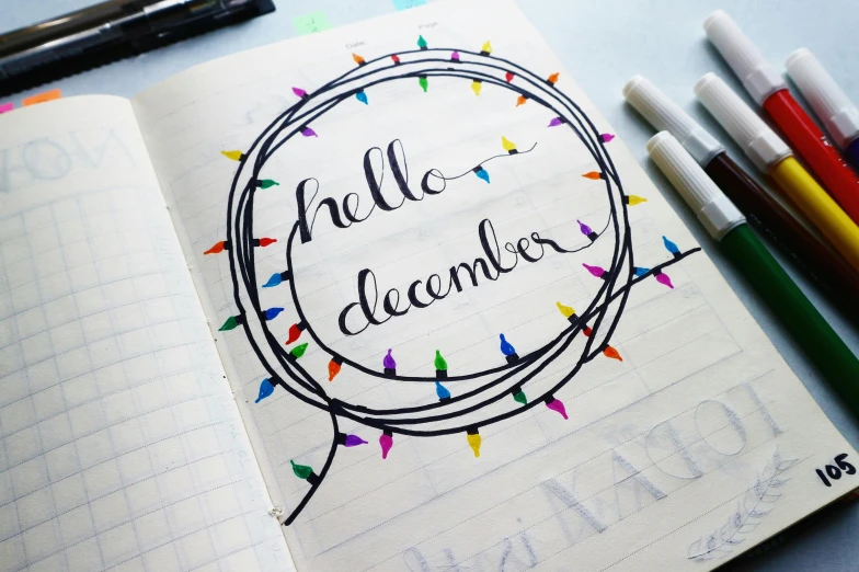 a notebook with markers that say hello december