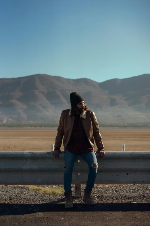 a man sitting on top of a wall next to the road