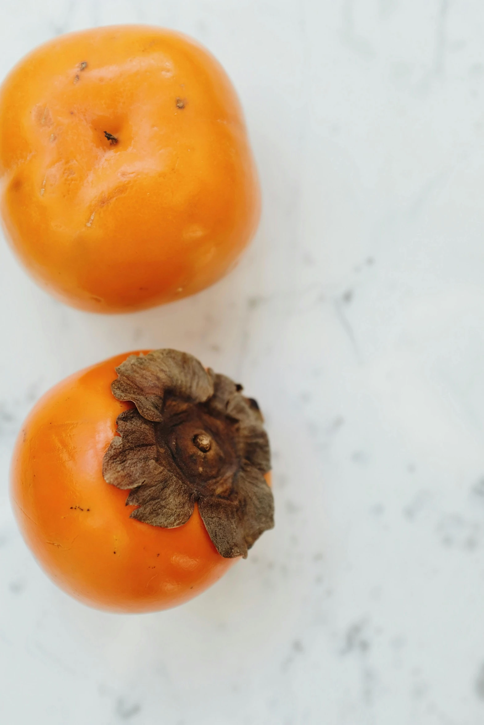 a couple of oranges sitting on top of a table, obsidian pomegranade, top - down photograph, viewed from the side, poppy