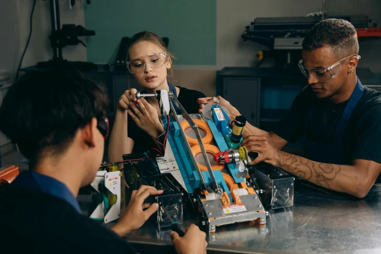 a group of people sitting around a table working on a robot, a portrait, starting engines nitro jet drive, working in her science lab, profile image, thumbnail