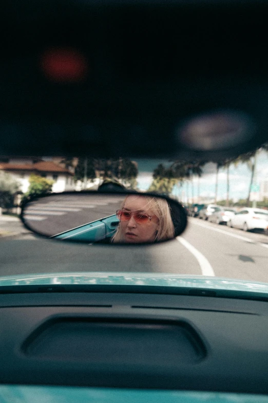 the reflection in the side view mirror of an old woman driving