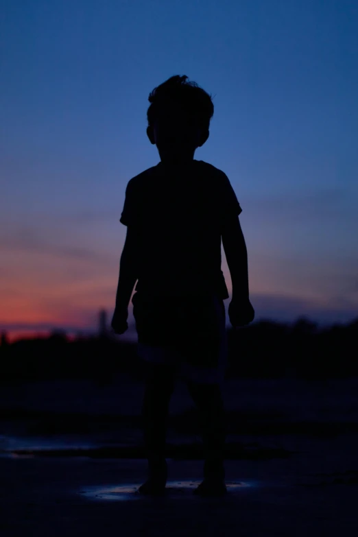 a silhouette of a child standing in a puddle of water, by Brad Holland, pexels, dusk sky, confident stance, innocent face, low iso