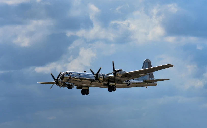 a large propeller plane flying through a cloudy sky, by Jim Nelson, pexels contest winner, hurufiyya, preserved historical, shiny silver, large blue engines, hercules brabazon