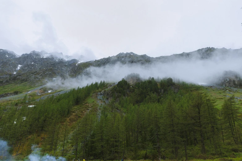 a smokey area in front of a green mountain with fog