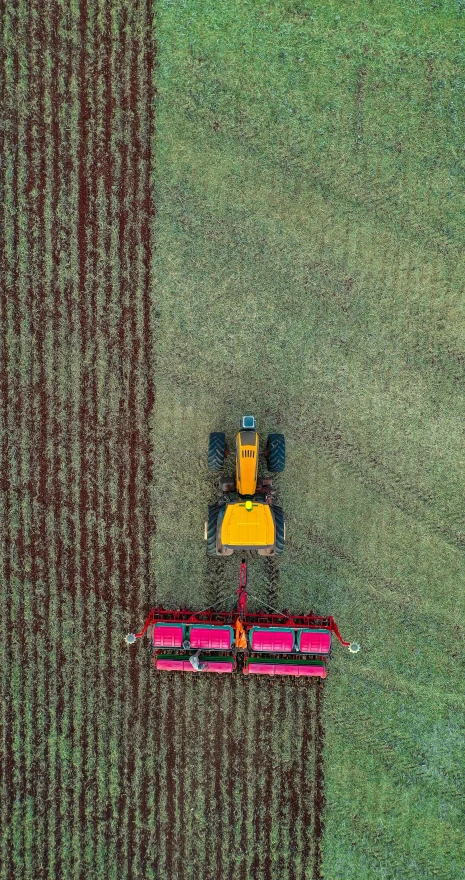 an aerial view of a tractor plowing a field, a digital rendering, by Andries Stock, unsplash contest winner, yellow and red, 15081959 21121991 01012000 4k, australia, sustainability