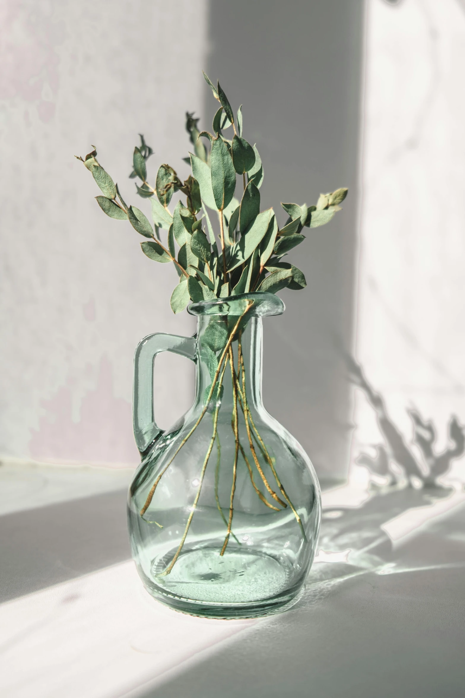 a clear glass vase with greenery in it