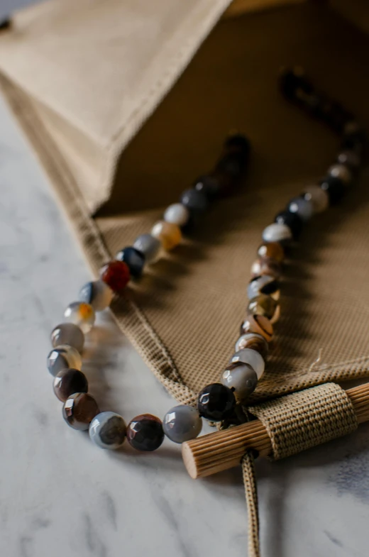 a close up of a beaded necklace on a table, inspired by Kanō Hōgai, unsplash, agate, casually dressed, 1 6 x 1 6, bamboo