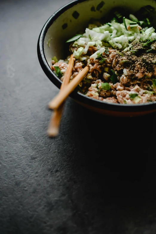 a close up of a bowl of food with chopsticks, unsplash, mingei, ground meat, herbs, square, kete butcher