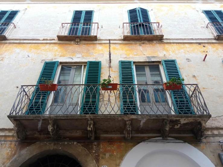 a building with blue shutters and green shutters, an album cover, inspired by Carlo Maderna, pexels contest winner, renaissance, balcony, turquoise rust, square, teal silver red