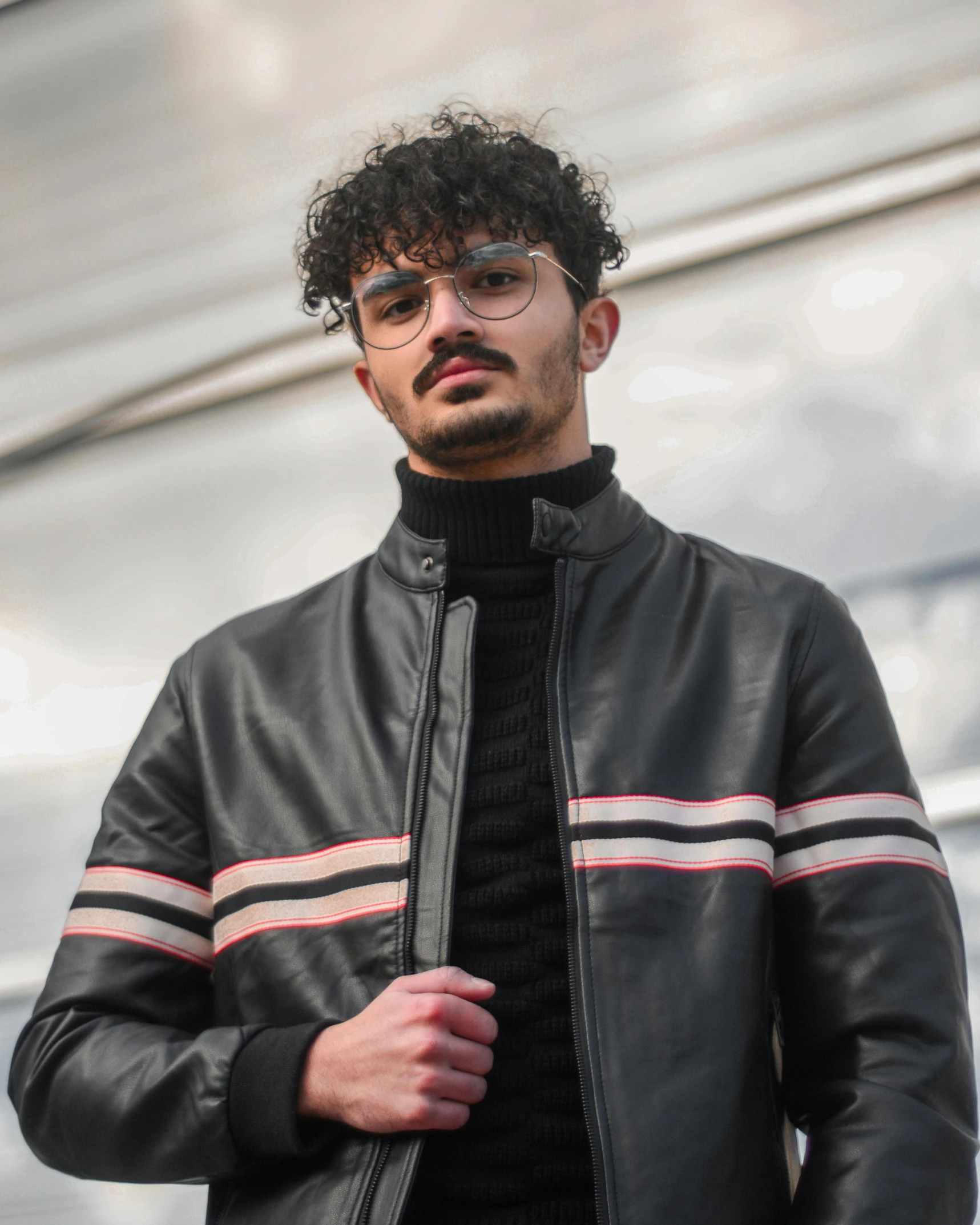 man wearing glasses, black and grey jacket with striped sleeves and moustache