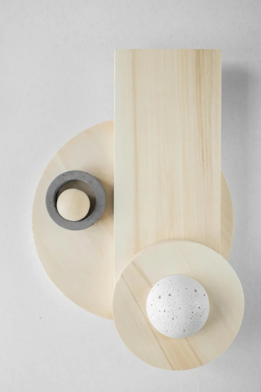 a white egg sitting on top of a wooden board, an abstract sculpture, inspired by Isamu Noguchi, kinetic art, sconces, hues of subtle grey, detailed product image, circle forms