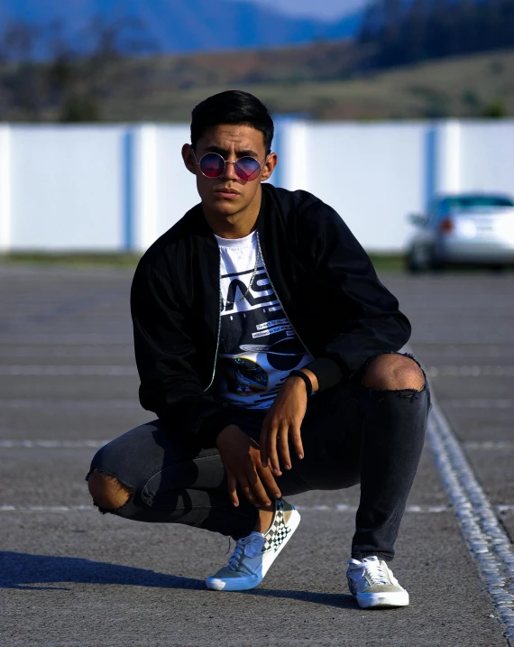 young man crouched down outside in a parking lot