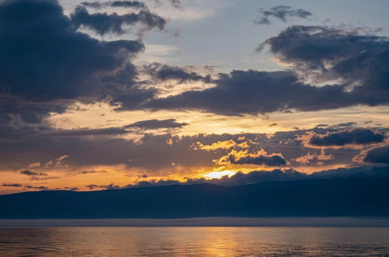 the sun is setting over water with clouds