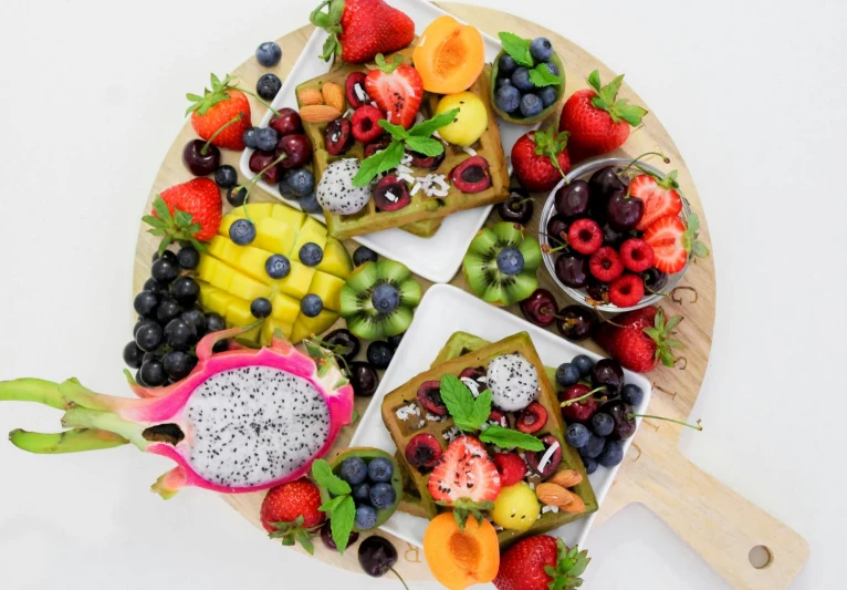 a wooden cutting board topped with assorted fruit, hurufiyya, colourful explosion, on a white table, 🎀 🗡 🍓 🧚, 278122496