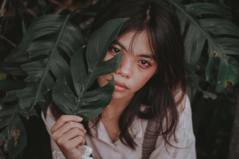 a woman holding a leaf in front of her face, trending on pexels, sumatraism, looking seductive, woman made of plants, teenage girl, ilustration