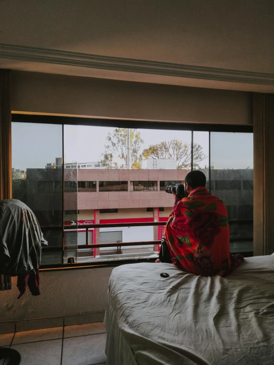 a person sitting on a bed looking out a window