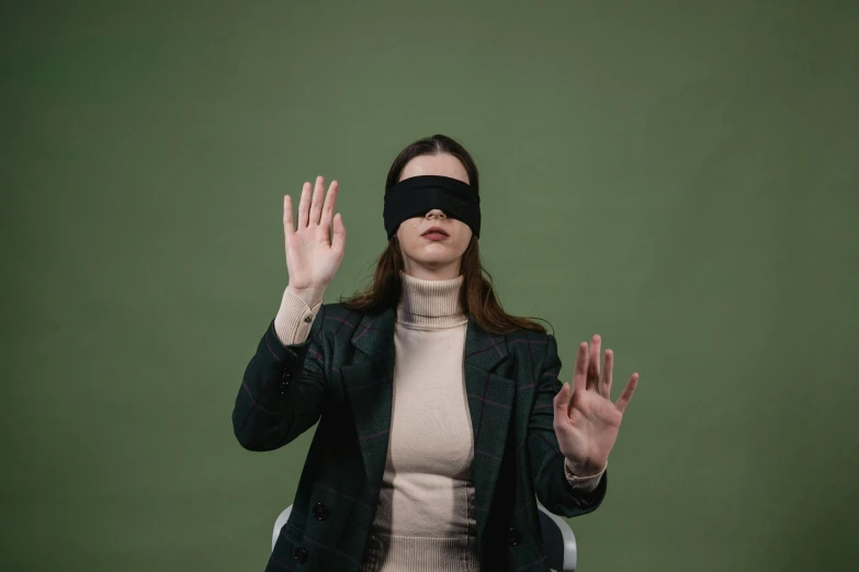 a woman is dressed in a blindfold and has her arms stretched out to the sides