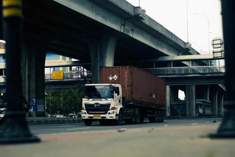 a truck traveling under a bridge over a city street