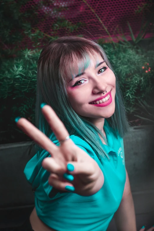 a woman wearing turquoise makeup making an okay sign