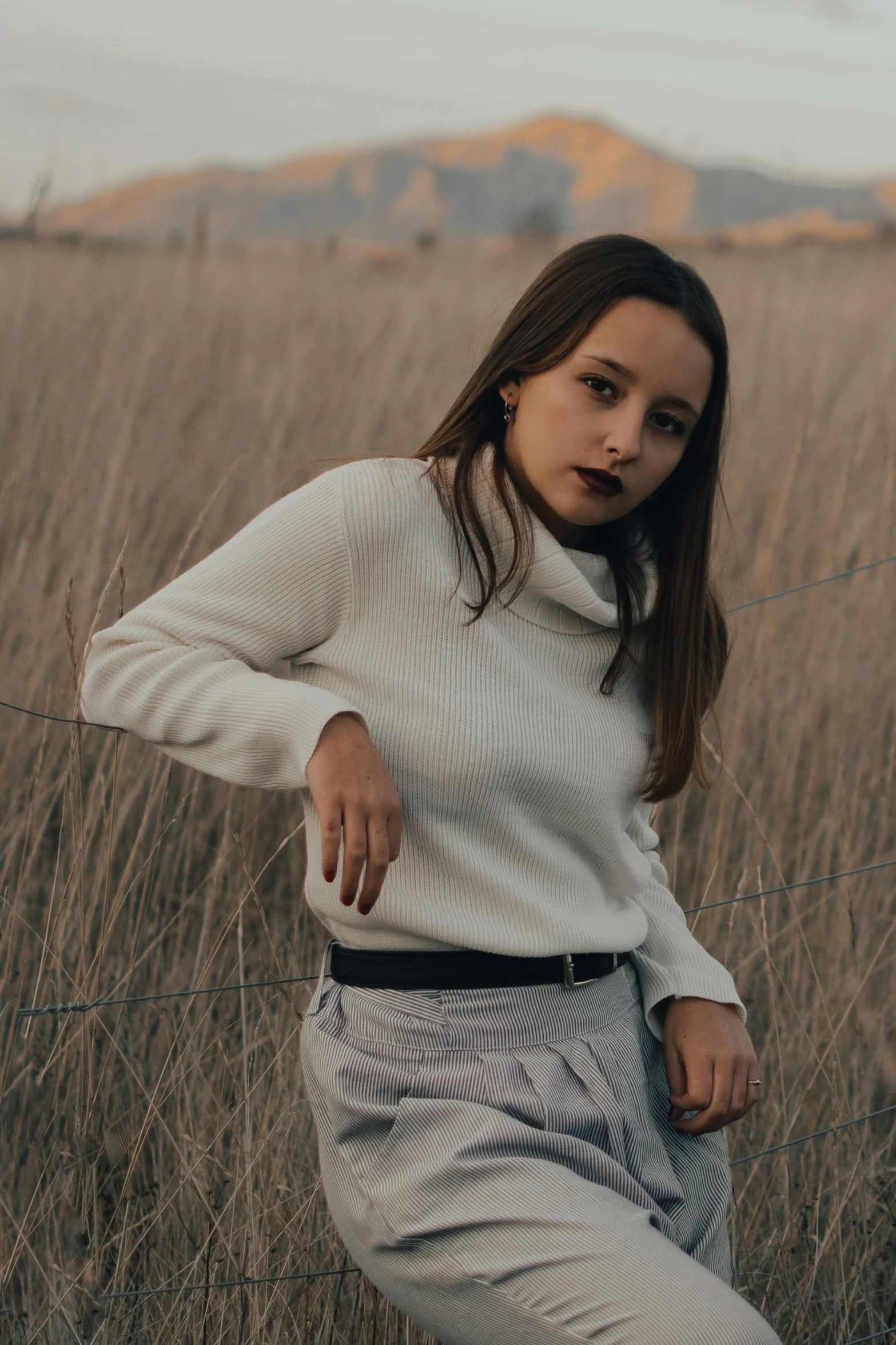 a woman standing in a field of tall grass, inspired by Elsa Bleda, trending on pexels, renaissance, in white turtleneck shirt, wearing casual sweater, plain background, 5 0 0 px models