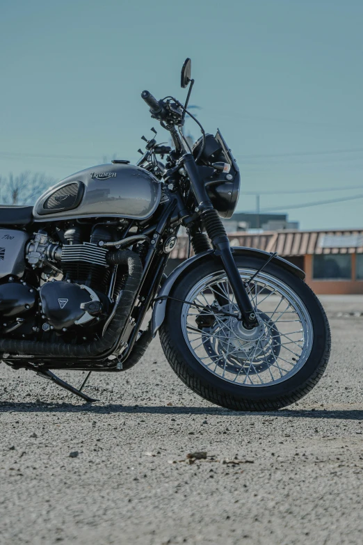 a black motorcycle parked in a parking lot, by Tom Bonson, unsplash, photorealism, triumph, steel gray body, brown, silver