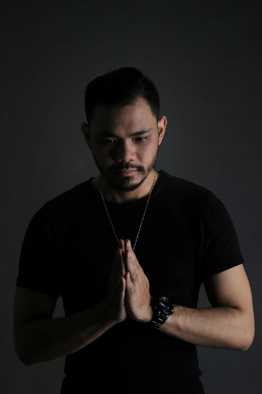 a man in a black shirt is praying, an album cover, inspired by Eddie Mendoza, unsplash, hurufiyya, malaysian, casual pose, dj, headshot profile picture