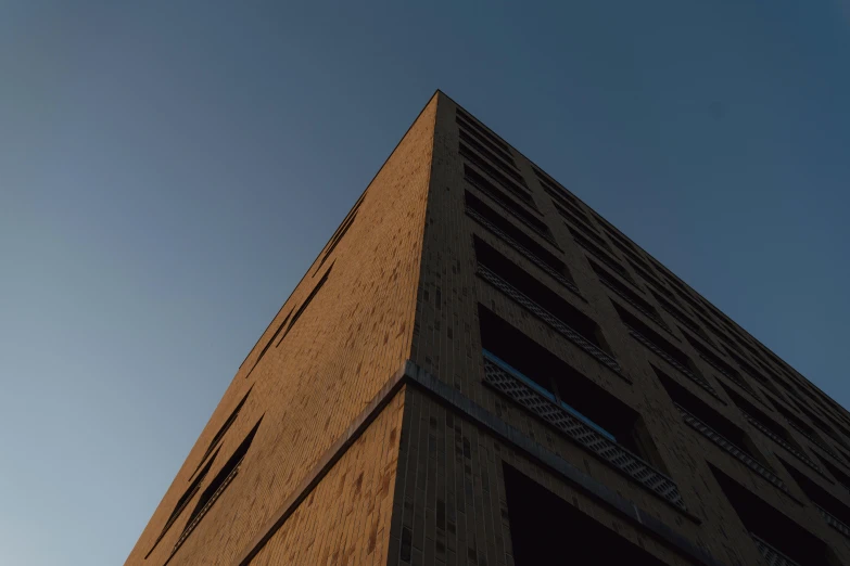 a tall brick building with a blue sky in the background, by Tobias Stimmer, unsplash, brutalism, dimly lit, vray 8k, low quality photo, brown