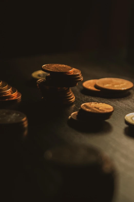 a pile of coins sitting on top of a table, a macro photograph, by Niko Henrichon, pexels contest winner, black and gold rich color, low-key, thumbnail, lofi
