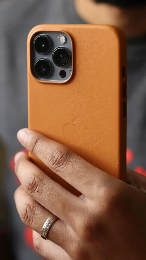 a close up of a person holding a cell phone, with brown skin, taken on iphone 1 3 pro, orange body, premium quality