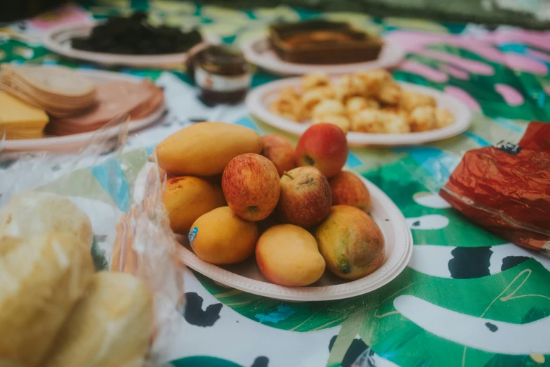 a table topped with plates of fruit and bread, unsplash, jungle fruit, festival, background image, manuka