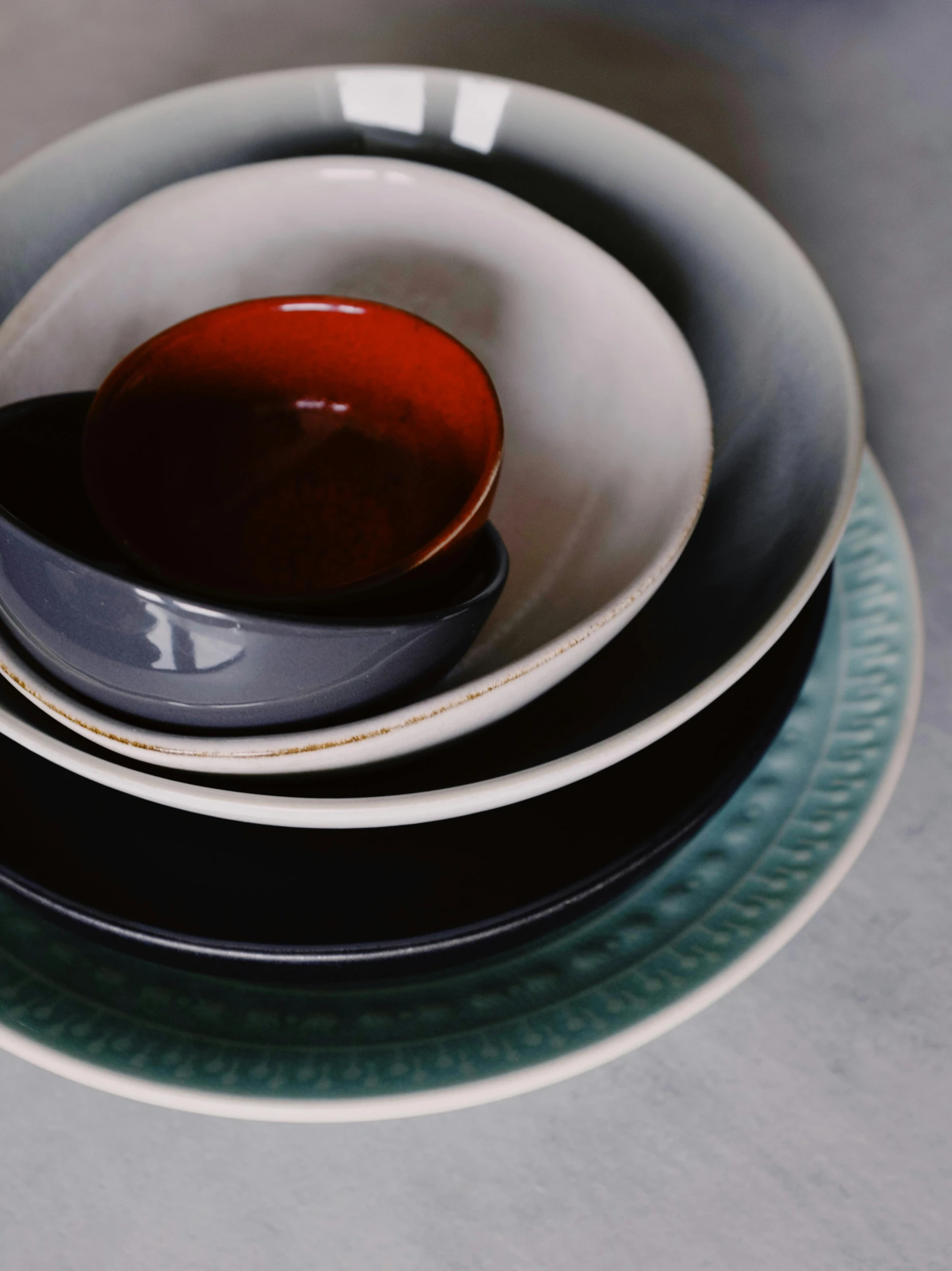 a stack of plates sitting on top of a table, a still life, by Fuller Potter, trending on unsplash, dark blue + dark orange, made of glazed, medium closeup, viridian and venetian red