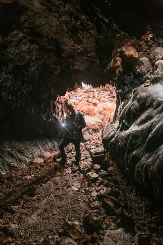 person standing in cave area with camera in hands