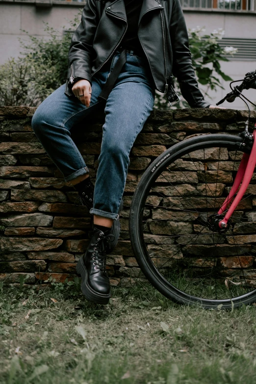 a man sitting on top of a brick wall next to a red bike