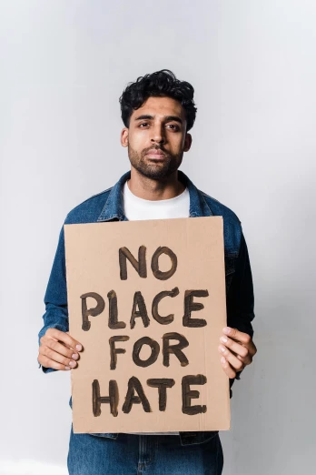 a man holding a sign that reads no place for hate