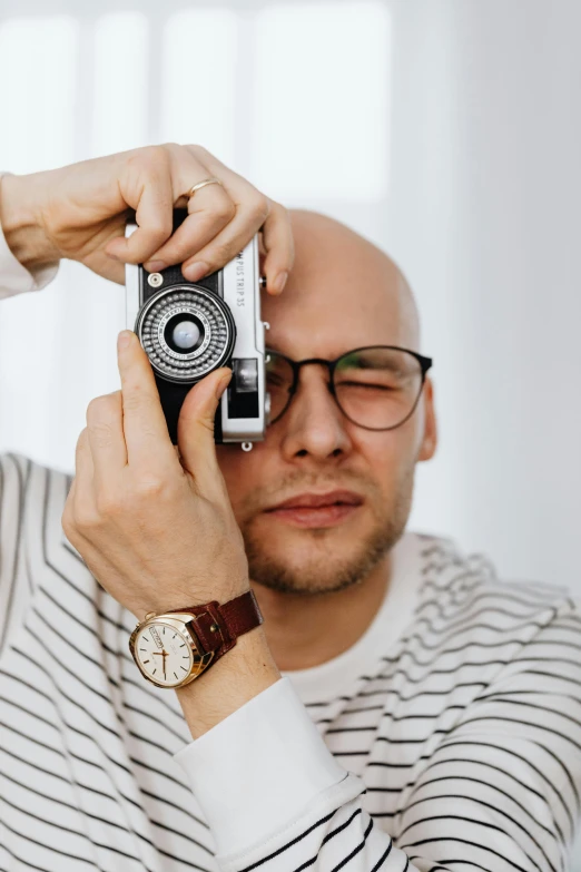 a man taking a picture with a camera, by Adam Marczyński, pexels contest winner, photorealism, square masculine facial features, portrait of bald, on a pale background, high quality picture