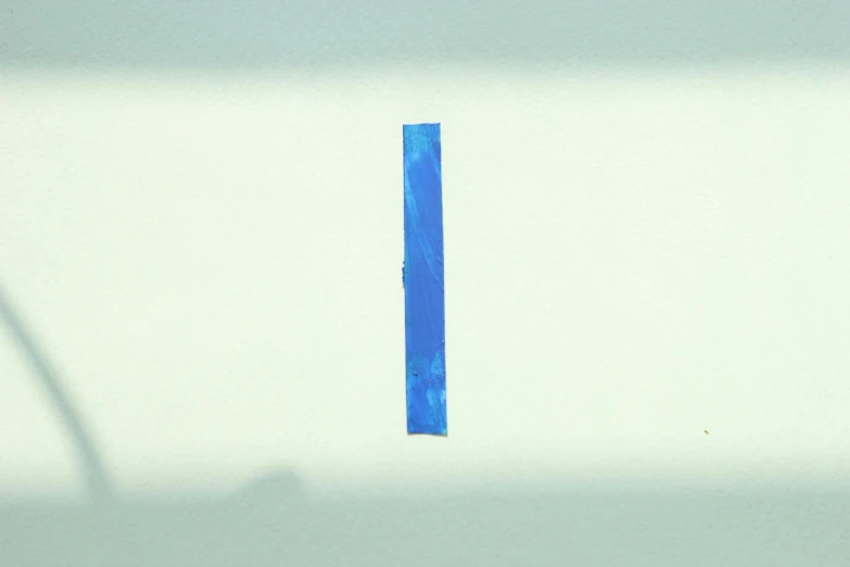 a blue tape sitting on top of a white wall, an album cover, inspired by Barnett Newman, unsplash, letter s, detailed - i, difraction from back light, portrait no. 1