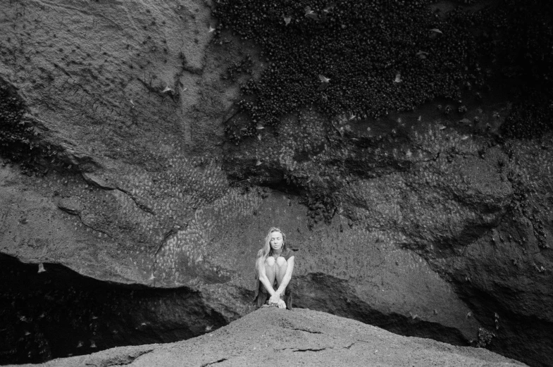 black and white pograph of woman sitting on rock