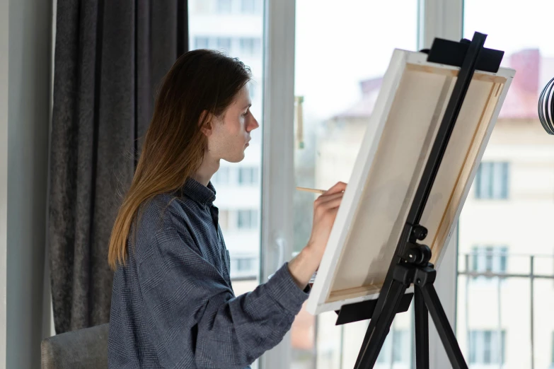 a woman painting on an easel in front of a window, pexels contest winner, academic art, tall female emo art student, on a white table, on canvas, afternoon lighting