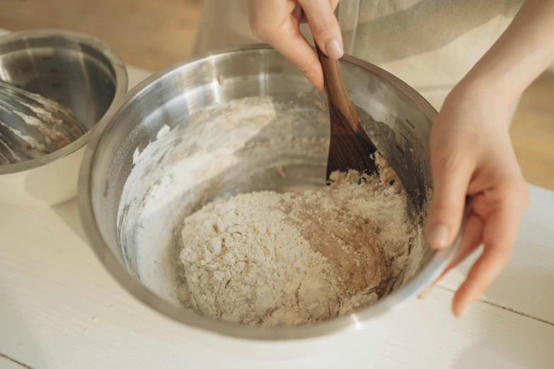 a woman mixing ingredients in a metal bowl, trending on pexels, covered in white flour, a wooden, thumbnail, low detail