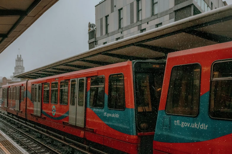 a red and blue train pulling into a train station, by Emma Andijewska, unsplash, snowy weather, underground metro, teal orange, thumbnail