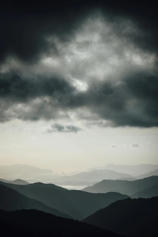 the foggy sky with dark clouds hangs over mountains