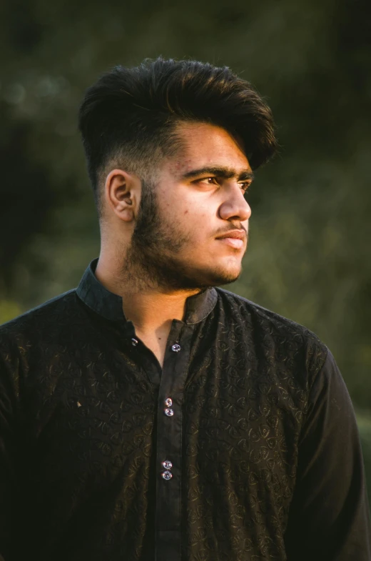 a man in a black shirt standing in a field, by Riza Abbasi, pexels contest winner, hurufiyya, thick jawline, male teenager, headshot profile picture, wearing a kurta